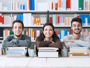a group of people sitting at a table in front of books.